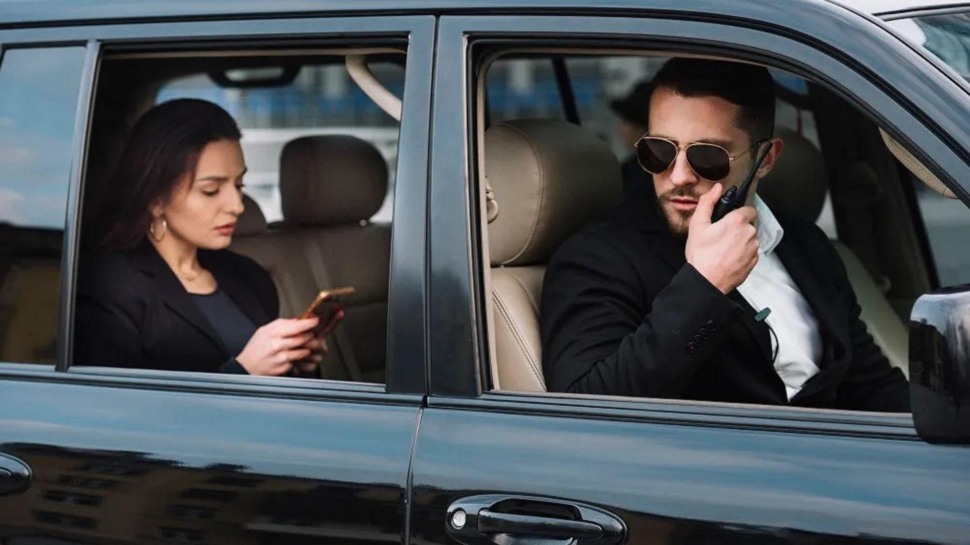 VIP passengers in the back of a private black SUV with a security escort