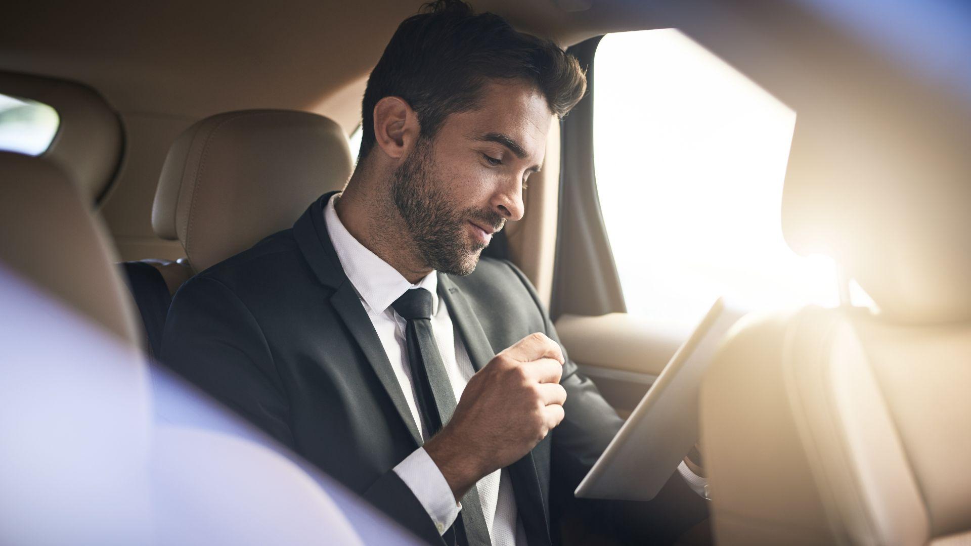 Executive working on a tablet in the back seat of a chauffeured luxury SUV in Chicago